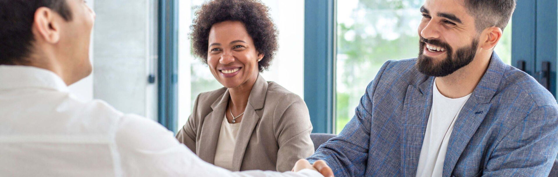 Drei Leute mit Handshake bei erfolgreichem Job Interview